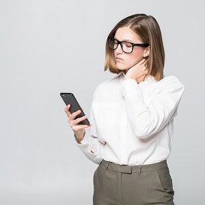 young pretty businesswoman looking phone screen holding neck pain isolated