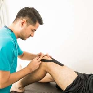 young physiotherapy professional applying kt tape athlete s knee hospital