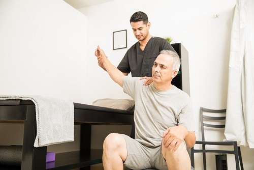 physiotherapist helping elderly patient with hand exercise physiotherapy clinic