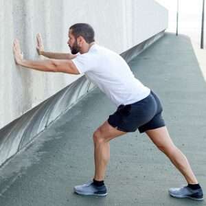 strong man stretching calf leaning wall