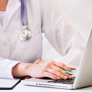 female doctor with stethoscope around her neck using laptop desk