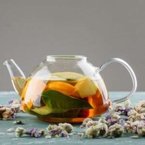 fruit infused water teapot with dried flowers side view plaster grey surface